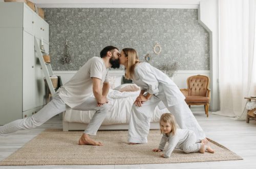 A family enjoying playful bonding moments in a stylish, minimalistic bedroom setting.